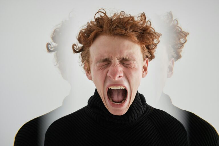 A man with red hair and black sweater yawning